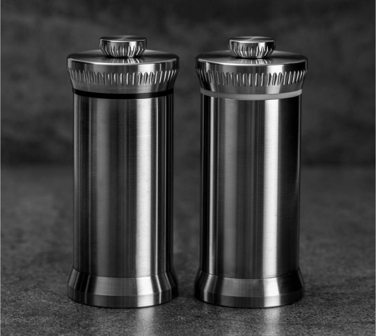 A pair of MILLD stainless steel mills on dark stone